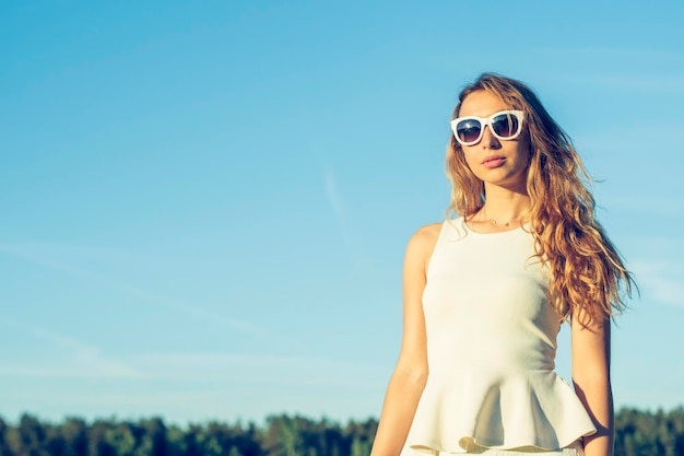 Zdjęcie portret młodej kobiety w okularach przeciwsłonecznych na tle nieba