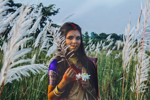 Zdjęcie portret młodej kobiety w sari trzymającej roślinę na lądzie