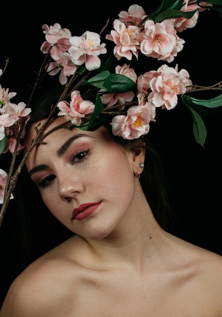 Portret młodej kobiety w topless z kwiatami na czarnym tle