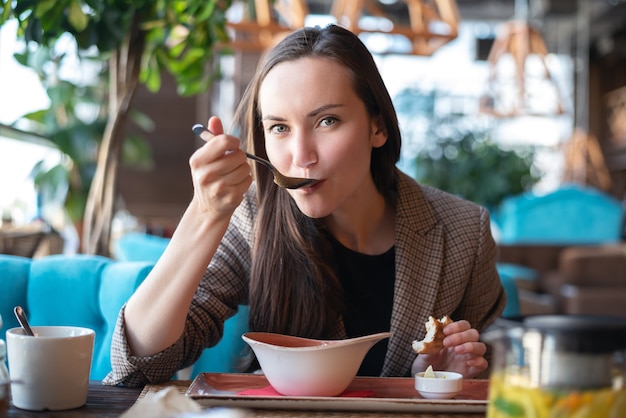 Portret młodej kobiety we wnętrzu restauracji przy stole jedzenia zupy z chlebem, niewyraźne