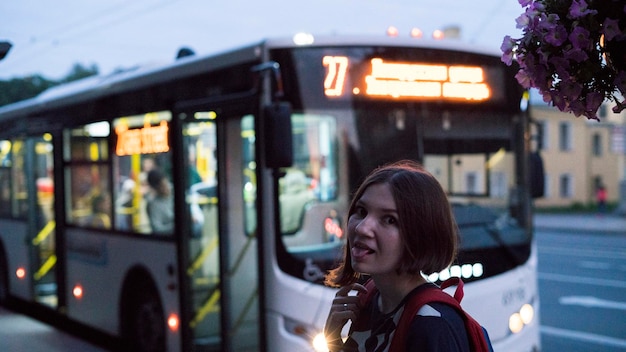 Portret młodej kobiety wystawiającej język na autobus w mieście