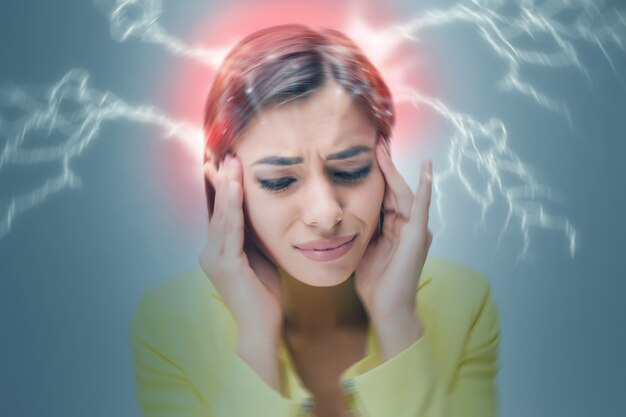 Portret Młodej Kobiety Z Bólowymi Emocjami Na Szarym Tle. Koncepcja Bólu Głowy. Zamazany Obraz