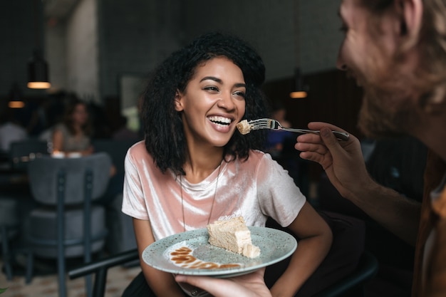 Portret młodej kobiety z ciemnymi włosami kręconymi, jedzenie ciasta w restauracji