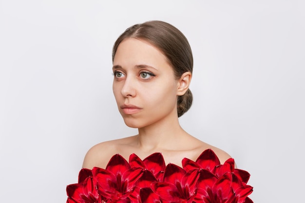 Portret młodej kobiety z czerwonymi kwiatami lilii zamiast ubrań na białym tle