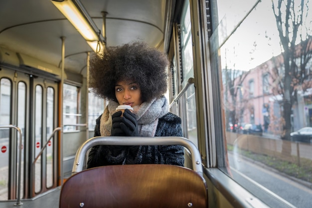 Portret młodej kobiety z filiżanką kawy siedzącej w autobusie