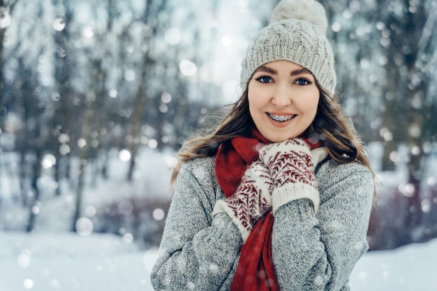 Portret młodej kobiety zima. Piękna radosna modelka Dziewczyna śmieje się i świetnie się bawi w winter park. Piękna młoda kobieta na zewnątrz, cieszyć się przyrodą, zima