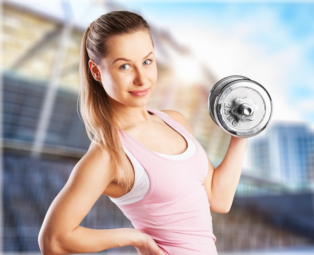 Zdjęcie portret młodej ładnej kobiety trzymającej ciężary i uprawiającej fitness w pomieszczeniu