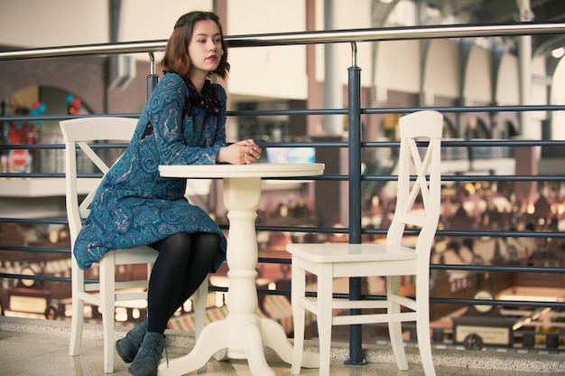 Portret młodej marzycielskiej kobiety siedzącej w kawiarni