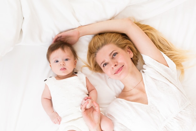 Portret młodej matki o blond włosach z jej słodką 3-miesięczną córeczką