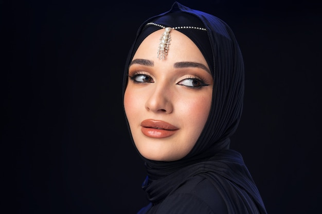 Portret młodej muzułmańskiej kobiety w hidżabie na czarnym tle