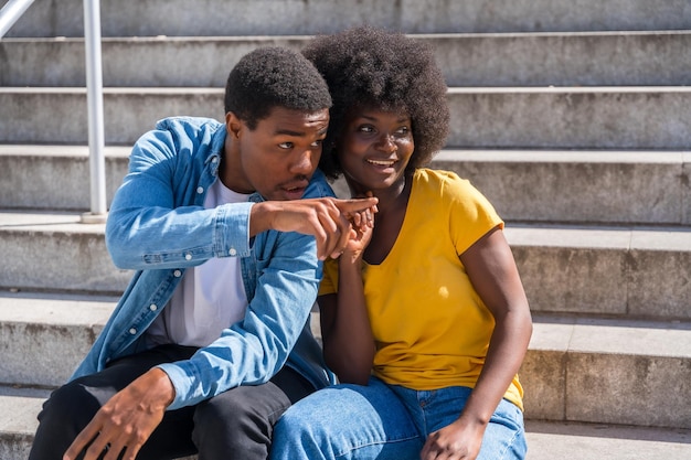 Portret młodej pary czarnej rasy etnicznej siedzącej w mieście na schodach