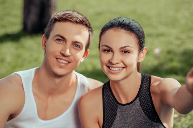 Portret młodej pary sportowców uśmiechających się do kamery w parku