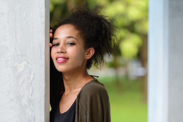 Portret młodej pięknej afrykańskiej kobiety z Afro włosów relaks w parku na świeżym powietrzu