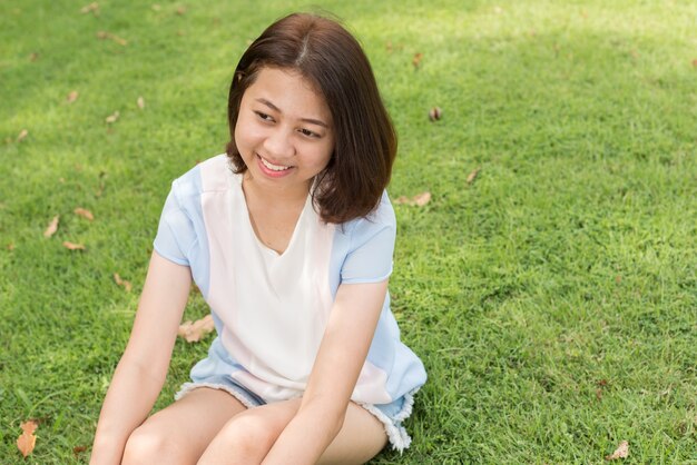 Portret młodej pięknej azjatyckiej nastolatki relaks w parku na świeżym powietrzu