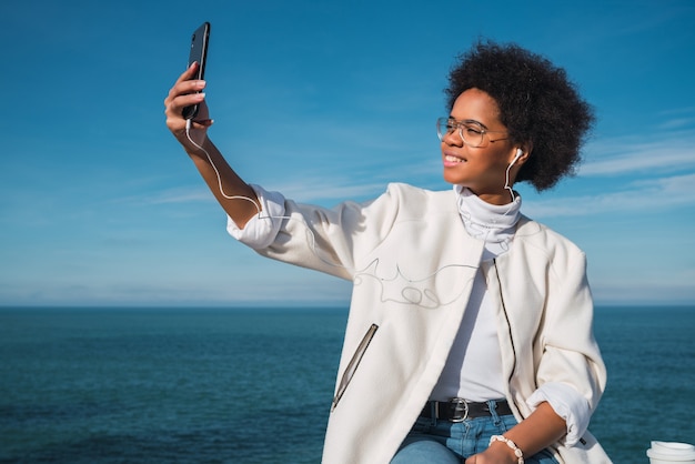 Portret Młodej Pięknej Kobiety łacińskiej Robienia Selfie Z Telefonu Komórkowego Na Zewnątrz Z Morzem W Przestrzeni.