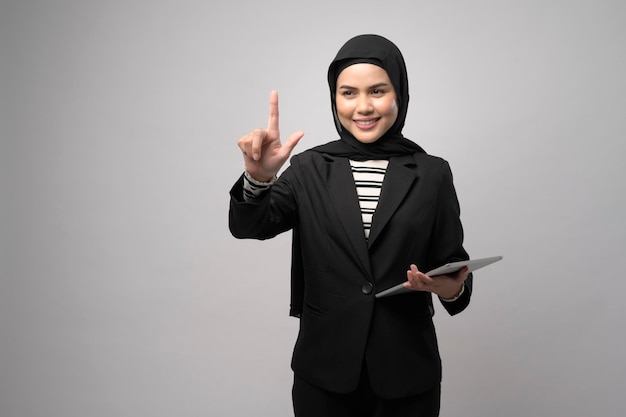 Portret młodej pięknej muzułmańskiej bizneswoman trzyma tablet na białym tle studio