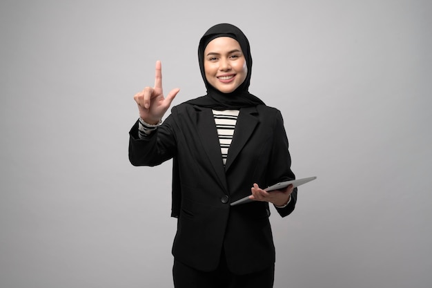 Portret młodej pięknej muzułmańskiej bizneswoman trzyma tablet na białym tle studio