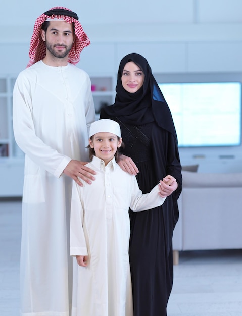 portret młodej szczęśliwej arabskiej muzułmańskiej rodziny z synem w tradycyjnych strojach spędzających razem czas w miesiącu Ramadan w domu