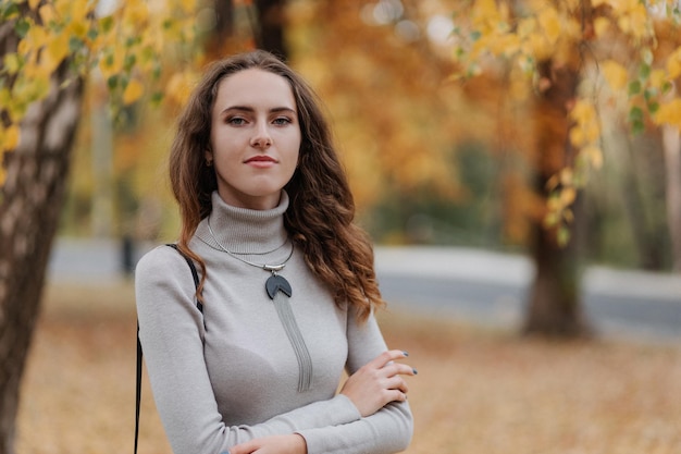 Portret Młodej Uśmiechniętej Dziewczyny W Szarej Sukience W Jesiennym Parku