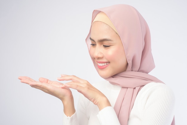Portret młodej uśmiechniętej muzułmańskiej kobiety ubrana w różowy hidżab na białym tle.