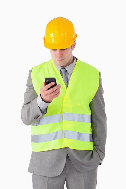 Portret młody budowniczy patrzeje jego telefon komórkowego