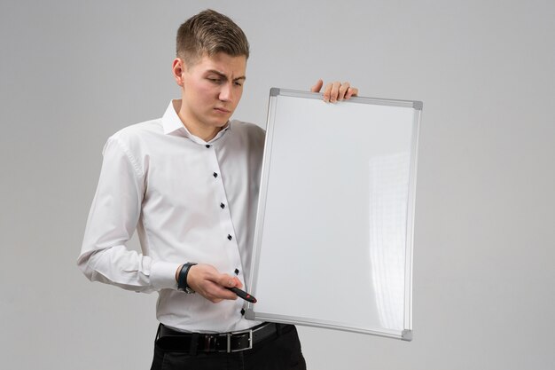 Portret młody człowiek z czystą magnesową deską i markier w jego rękach odizolowywać na białym tle