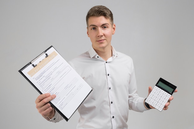 Portret młody człowiek z formą zapłaty rachunki i kalkulator w jego rękach odizolowywać na białym tshirt