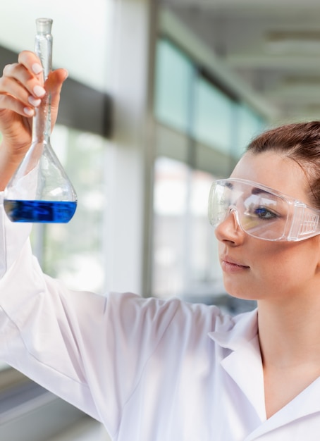Portret młody nauka uczeń patrzeje błękitnego ciecz w laboratorium
