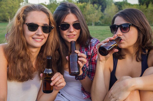 Zdjęcie portret młodych kobiet pijących alkohol siedzących na polu