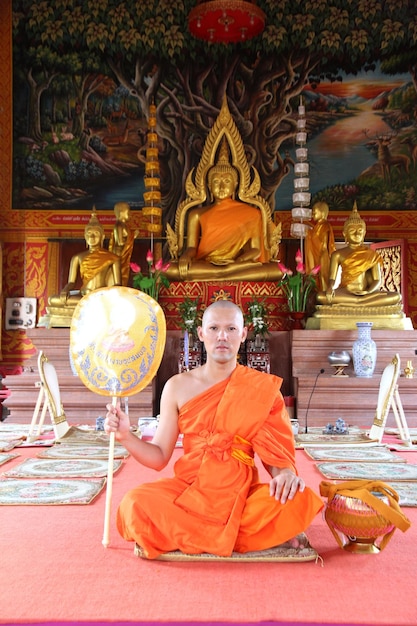 Zdjęcie portret mnicha siedzącego przy posągu buddy w świątyni