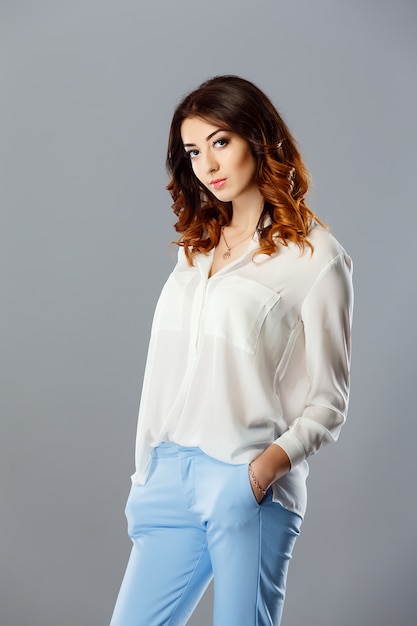 Zdjęcie portret modelki ubrane w niebieskie dżinsy i białą koszulę.