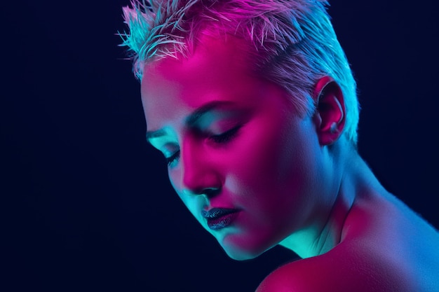 Portret modelki w świetle neonowym na ciemnym tle studio.