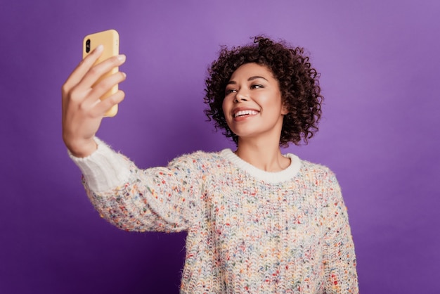 Portret modnej, uroczej dziewczyny, która trzyma telefon, sprawia, że selfie toothy uśmiech