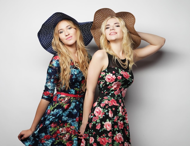 Portret mody dwóch stylowych, seksownych dziewcząt, najlepszych przyjaciół w sukienkach i kapeluszach.