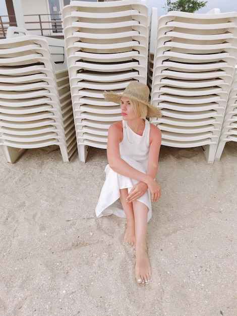 Portret mody młoda kobieta ma na sobie słomkowy kapelusz Zmysłowa dziewczyna siedzi na plaży z miejsca kopiowania Atrakcyjna dziewczyna patrząc na kamery