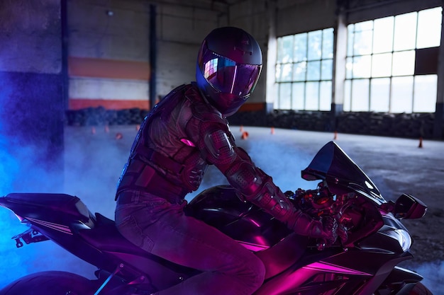 Portret motocyklisty w sprzęcie ochronnym i hełmie w świetle neonowym
