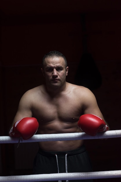 portret muskularnego profesjonalnego kickboxera, który stoi na ringu podczas treningu do walki