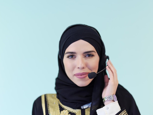 portret muzułmańskiej kobiety z szalikiem hidżabu przedstawicielka klienta kobieta biznesu z zestawem słuchawkowym telefonu pomagająca i wspierająca online z klientem w nowoczesnym call center na białym tle na cyjanowym tle