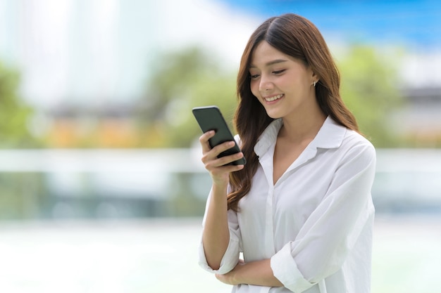 Portret na zewnątrz szczęśliwa młoda kobieta za pomocą telefonu w mieście