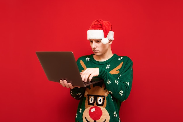 Portret nastolatek chłopiec z Christmas sweter gospodarstwa laptopa