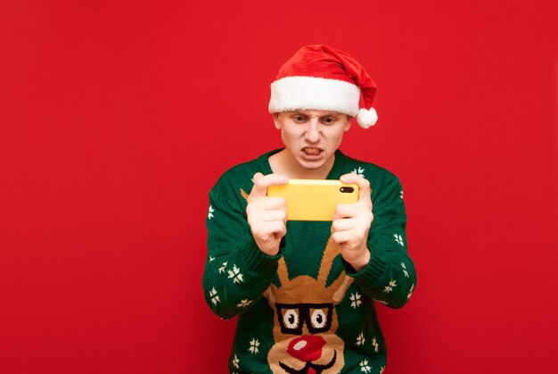 Portret nastolatek chłopiec z Christmas sweter trzymając telefon