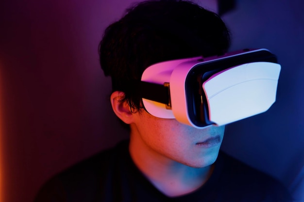 Portret nastolatka z okularami wirtualnej rzeczywistości i kolorowymi światłami