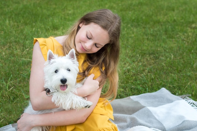 Portret nastoletniej dziewczyny na kratę w parku z psem West Terrier