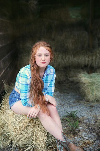 Zdjęcie portret nastoletniej dziewczyny siedzącej na balie siana