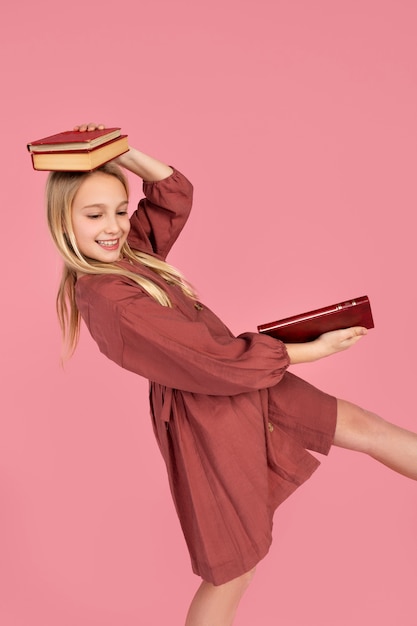 Zdjęcie portret nastoletniej dziewczyny trzymającej książki na głowie