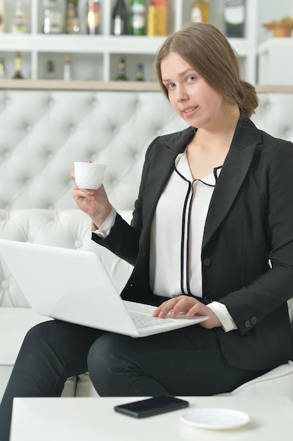 Portret nastoletniej dziewczyny w formalnym stroju za pomocą laptopa