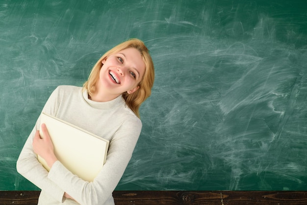 Zdjęcie portret nauczyciela młodego uśmiechniętego nauczyciela w klasie młodego zadowolonego profesora prof z folderem