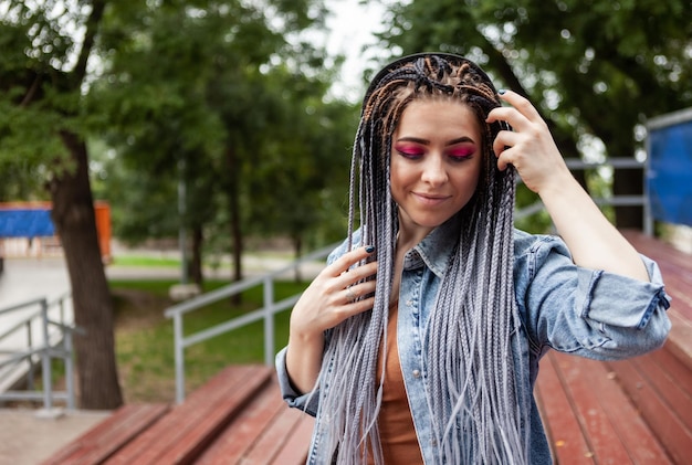 Portret nieformalnej kobiety z warkoczami afro i jasnym makijażem