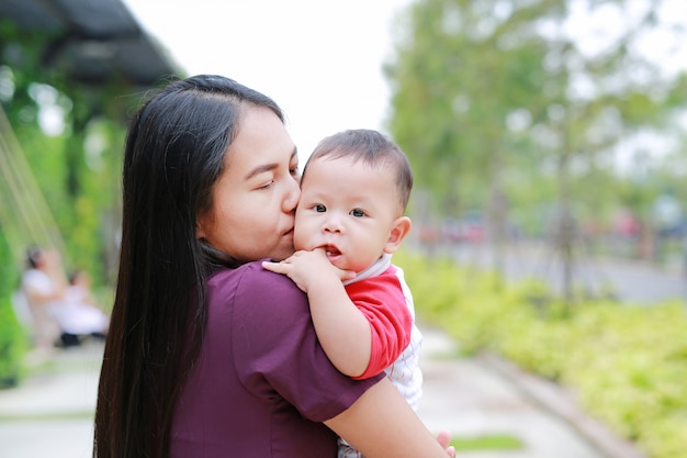 Portret niemowlęcia chłopiec ssący palec z Azji matki niosącej.