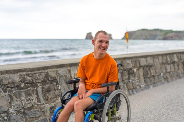 Portret niepełnosprawnej osoby na wózku inwalidzkim na plaży bawiącej się latem